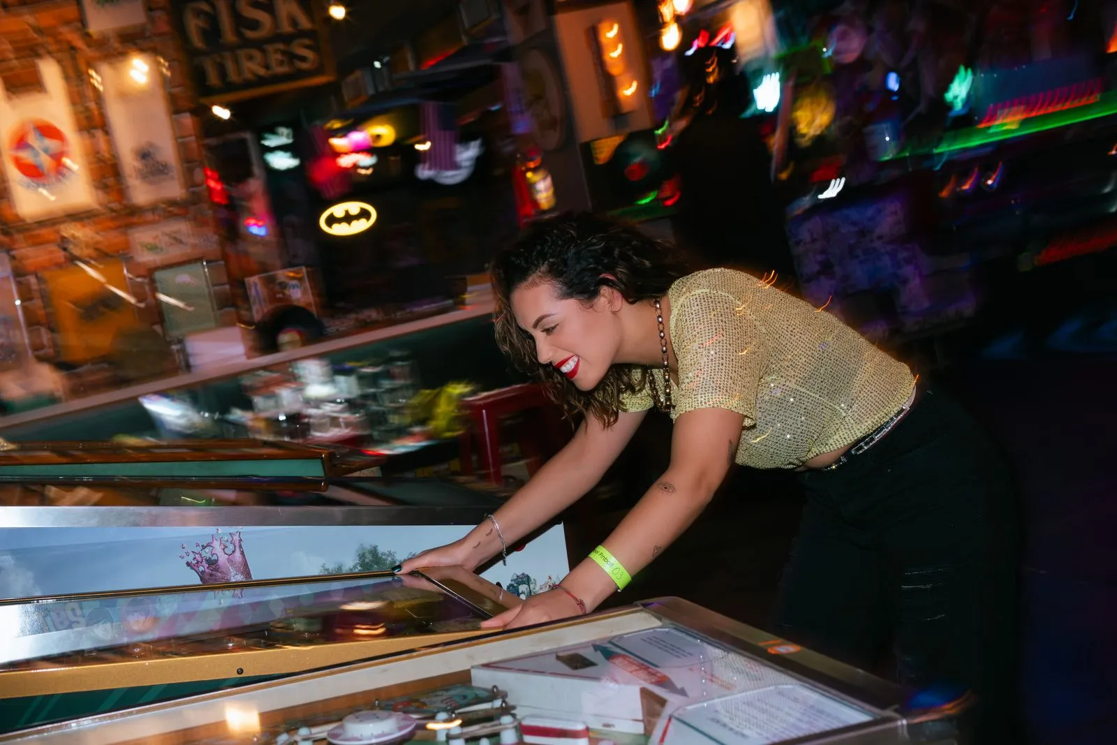 A woman cheerfully plays pinball in a vibrant, colorful arcade setting, embodying fun and entertainment.